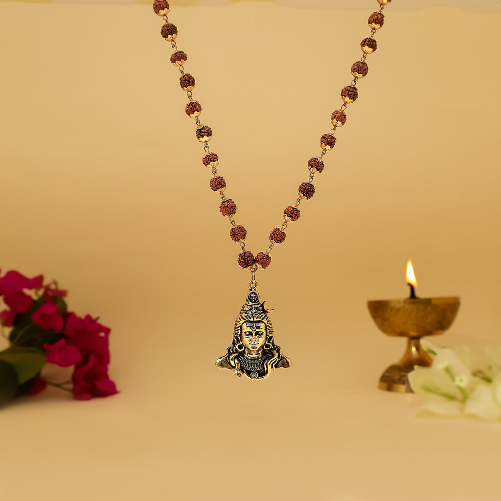 Rudraksha Necklace with shiva pendant on a beige background with flowers and a candle